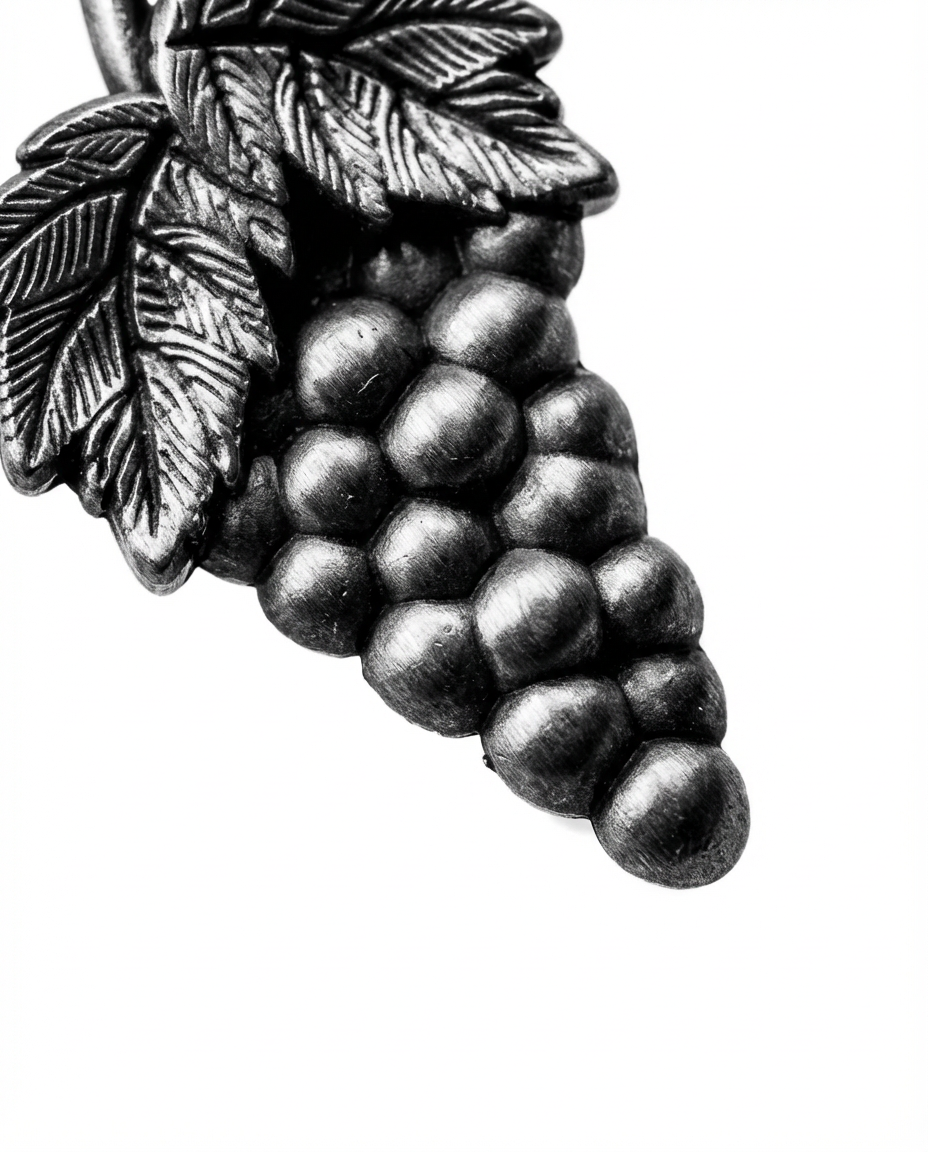 Close-up macro detail of antique silver sommelier pin showing grape texture for wine professionals